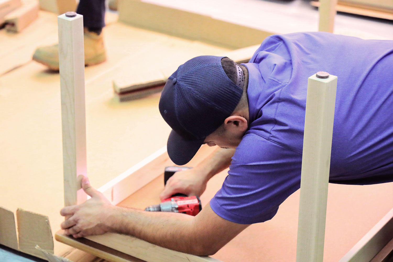 Person crouched while assembling wooden shelves.